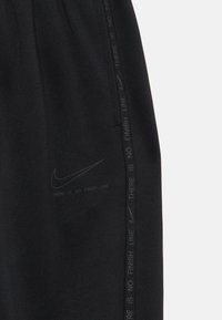Black sweatpants made from soft fabric, featuring a side stripe with text “THERE IS NO FINISH LINE” and a subtle Nike logo.