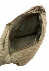 Sac à main matelassé beige avec une fermeture à glissière, offrant un intérieur spacieux et une petite poche zippée à l'intérieur pour l'organisation.