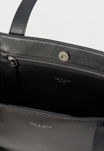 Μαύρη δερμάτινη τσάντα με ανοιχτό πάνω μέρος, εσωτερική τσέπη με ασημένιο φερμουάρ, κλείσιμο με κουμπί και τυπωμένο "rag & bone New York" σε λευκό.