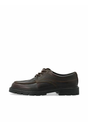 Chaussure en cuir marron foncé à lacets avec une épaisse semelle en caoutchouc noir et des coutures détaillées le long du bout et des panneaux latéraux.