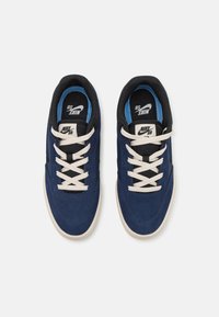Zili zamšaini sneakers ar melniem akcentiem, baltām šņorēm un vieglu zoli. Iekļauta mīksta apkure ap potīti un zīmols uz mēles un sāniem.