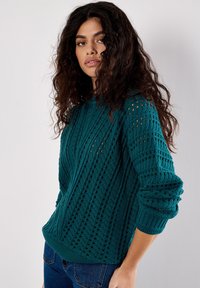 Maglione lavorato a maglia di colore teal con un motivo testurizzato caratterizzato da righe verticali e dettagli in pizzo. Le maniche e l'orlo a coste conferiscono struttura.