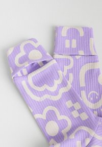 Chaussettes violettes à côtes ornées de motifs floraux et géométriques beiges. Le design comprend des contours nets et différentes formes sur le tissu.