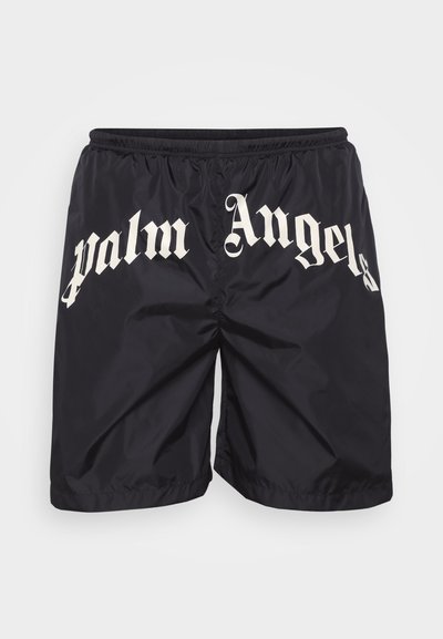 Melnas neilona šortus, kuriem priekšpusē liela, balta gotiskā fontā ir uzraksts "Palm Angels", un to elastīgais jostasviedrs.
