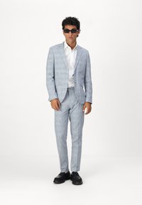 Light blue checked suit with a tailored fit, featuring a single button jacket and slim pants. Worn with a white shirt and black shoes.