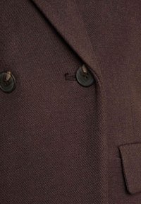 Brązowy żakiet wełniany o teksturowanym wykończeniu, z podwójnym zapięciem, dwoma ciemnymi guzikami i boczną kieszenią.