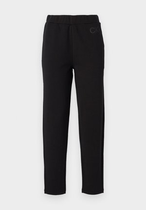 Black sweatpants with an elastic waistband, made of soft fabric. Features a subtle "CK" logo on the front. Straight leg design.