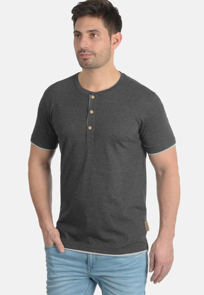 Dunkelgraues kurzärmliges Henley-Shirt mit fünf Holzknöpfen am Ausschnitt, abgerundetem Saum und hellgrauen Akzenten an den Ärmeln und dem Kragen.