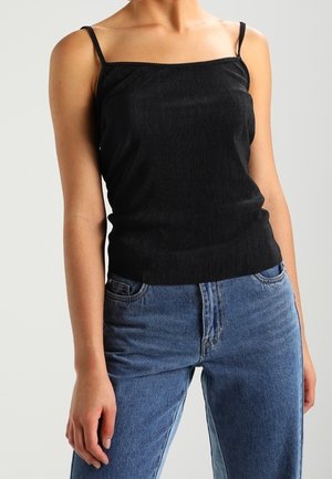 Zwart geribd tanktopje met smalle bandjes, voorzien van een vierkante halslijn en een getailleerd silhouet, gecombineerd met high-waisted blauwe spijkerbroek.