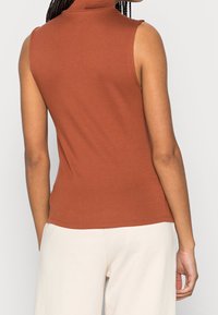 Haut sans manches à col montant en mélange de coton couleur rouille. Présente une silhouette ajustée et une texture lisse. Vue de dos avec des coutures minimales.