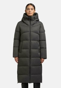 Cappotto lungo imbottito di colore grigio scuro con colletto alto, chiusura con zip e tasche laterali; presenta un tessuto testurizzato e un motivo a blocchi.