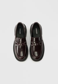 Burgundi värvi nahast loafers mustal paksul taldal, hõbedase pandlaga detailiga ja siledat, läikivat viimistlust.