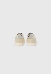 Low-top sneakers in beige and cream, featuring textured suede and smooth leather accents, with a cushioned sole and looped heel tabs.