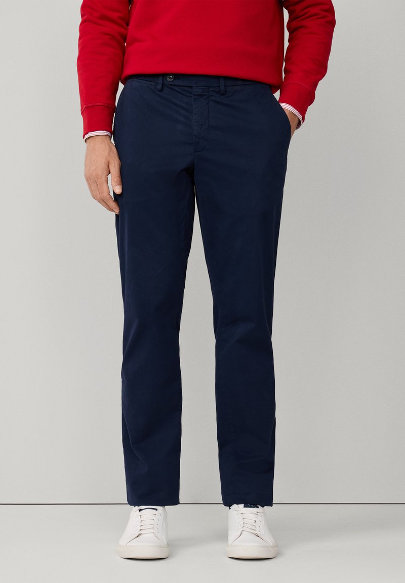 Pantalones ajustados azul marino con un diseño clásico, hechos de tejido de algodón suave, con bolsillos laterales y un estrechamiento gradual en el tobillo.