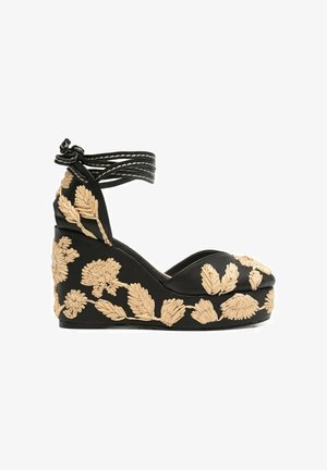 Sandalo zeppa nero con ricamo floreale marrone chiaro e cinturini da avvolgere alla caviglia, annodati a fiocco.