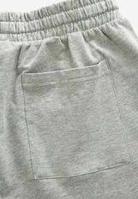 Gray cotton joggers feature an elastic waistband and a stitched rear pocket, showcasing a soft texture and a simple design.