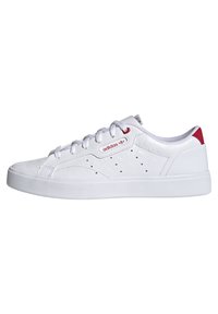 Vita sneakers med en slät, texturerad överdel, som har röda accenter, perforerade detaljer och vita snören. Logotyp på sidan.