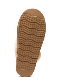 Tan rubber outsole with a wavy pattern and raised dots for traction. Soft, fluffy upper material not visible, focusing on the sole design.