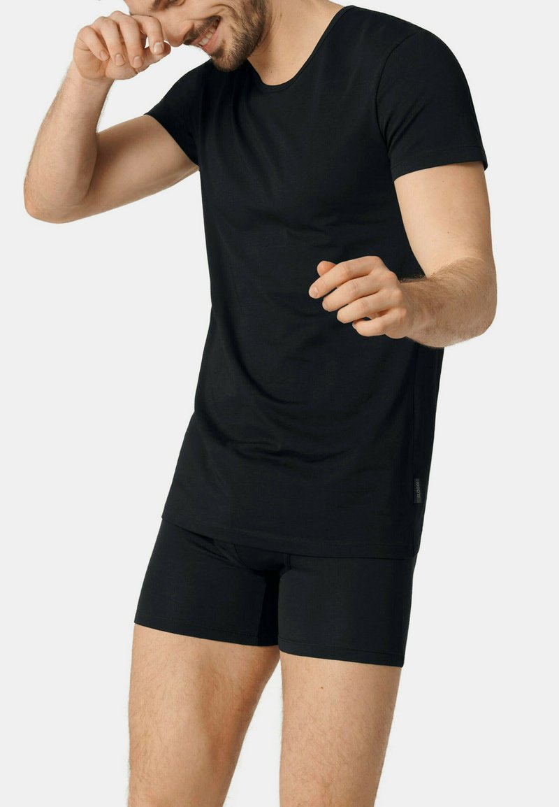 Black cotton T-shirt with short sleeves and a round neckline, paired with black fitted boxer shorts. Smooth texture, no visible patterns or logos.
