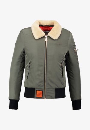 Veste bomber vert olive avec un col en fausse fourrure, fermeture éclair dorée à l'avant, deux poches latérales et un ourlet texturé avec des côtes aux poignets. Détail d'étiquette orange à l'avant.
