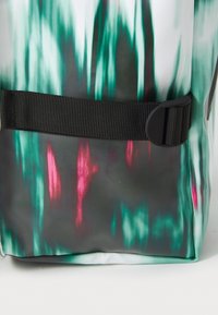 Vattentät totebag med ett grönt och grått mönster med rosa detaljer. Inkluderar ett svart justerbart band och plastdetaljer.