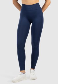 Marina högmidjade leggings tillverkade av elastiskt material. Slät textur, figurnära design och ankellängd med ribbad midja.