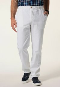 Vita linbyxor med rak passform, två sidofickor och knappstängning, kombinerat med mörkblå sneakers.