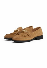Brown suede loafers with a flat black sole, decorative gold chain detail, fringed accents on the front, and a rounded toe design.