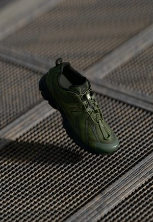 Sapatilha atlética verde com parte superior texturizada, sistema de atacadores e colarinho acolchoado. Dispõe de uma sola de borracha espessa e detalhes refletivos.