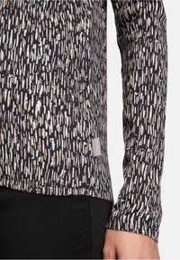 Langarmshirt mit navyfarbenem Grund und strukturiertem Muster aus vertikalen weißen und beigen Linien; enthält ein kleines Markenlabel am Saum.