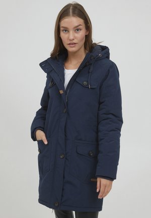 Navyblauwe parka met capuchon, ritssluiting en knoopsluiting, twee zijzakken en een textuurstof. Inclusief verstelbare koordjes en logodetail.