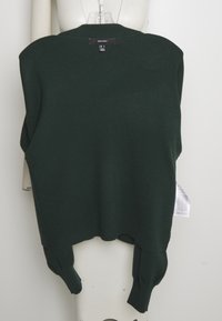 Tummanvihreä neulepusero, jossa rento muoto, resorinen kaula-aukko ja hihat sekä takana oleva lappu. Pehmeä pinta ja sivuilla halkiot.