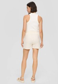 Lichtbeige mouwloos topje gecombineerd met bijpassende shorts, gemaakt van zachte, lichte stof met een elastische tailleband. Simpel, schoon ontwerp.