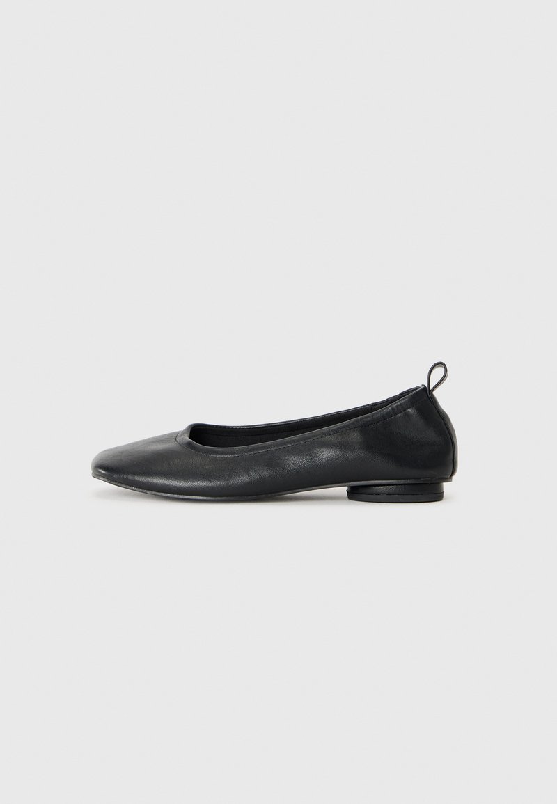 Ballerines en cuir noir avec un bout arrondi, un talon bas et une lisière élastiquée ; texture lisse avec des coutures minimales.