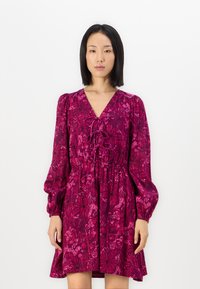 Robe fuchsia avec un décolleté en V, des manches bouffantes et une taille froncée. Présente un motif floral et des détails à lacets à l'avant.