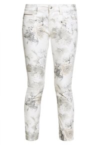 Białe dżinsy w kwiatowy wzór z jasnoszarymi ilustracjami kwiatów i liści, o wąskim kroju i srebrnymi detalami.