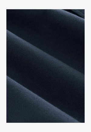 Mørkeblå stof med en tekstureret overflade, præget af glatte folder og et ensartet vævemønster, der reflekterer lys i subtile nuancer.