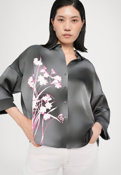 Bluză din satin de culoare gri închis, cu un model floral mare în nuanțe de roz pe partea stângă, având un gât cu nasturi și mâneci relaxate.