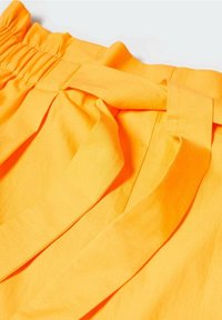 Tessuto giallo brillante con vita arricciata, caratterizzato da sezioni sovrapposte e un dettaglio annodato. Texture liscia, aspetto leggero.