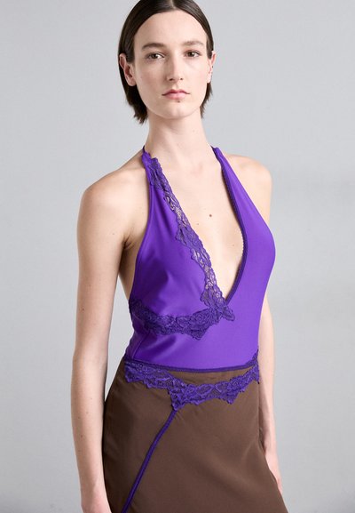 Paarse halter-stijl bodysuit met kantaccenten, gecombineerd met een bruine rok met kantafwerking en een strakke silhouet.
