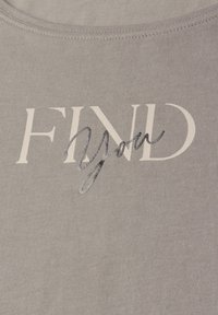 T-shirt en coton gris avec une texture côtelée, affichant le mot "FIND" en blanc et "You" en script noir brillant en dessous.
