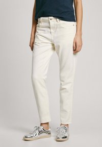Off-white jeans iz ravnim krojem, ki vključujejo pet žepov in podrobnosti v rumeni barvi, v kombinaciji s srebrnimi supergami.