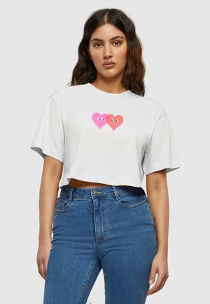 Weißes, cropped T-Shirt aus Baumwolle mit einem pinken und roten Herz-Design, das in der Mitte lächelnde Gesichter zeigt, kurzen Ärmeln und einem runden Ausschnitt.