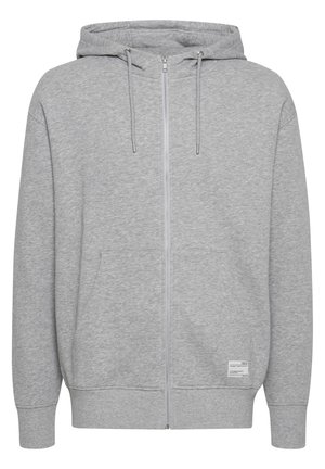 Svetlo siva zip-up kapuca z sprednjimi žepi, kapuco z vrvico, rebraste manšete in majhno belo označevalno nalepko blizu roba na sprednji desni strani.