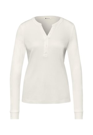 Valkoinen pitkähihainen henley-paita, jossa on pyöreä pääntie ja viisi nappia edessä keskellä olevan aukon varrella.