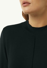 Maglietta nera a collo alto con una texture morbida. Presenta un dettaglio di cucitura e un colletto a coste, che conferisce un aspetto aderente alla scollatura.