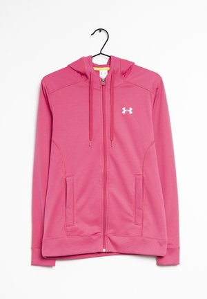 Růžová mikina na zip s kapucí, se zavazovacími šňůrkami, bočními kapsami a bílým logem Under Armour na hrudi, zavěšená na černém ramínku.
