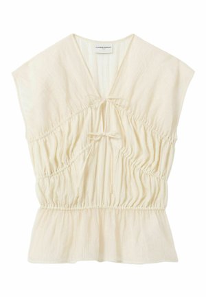 Blusa ligera color crema con mangas cortas tipo capa, escote en V, dos cierres delanteros con lazo, cintura fruncida y dobladillo ligeramente acampanado.