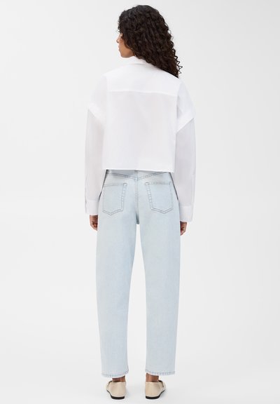Valge lühike särk klassikalise kraega, mis on kombineeritud helesiniste kõrge talje denimitega. Pehme kangas, mugav lõige ja delikaatsed õmblemise detailid.
