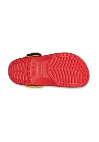 Rode rubberen zool van een schoen met een gestructureerd loopvlakpatroon, met zwarte en gele accenten zichtbaar langs de randen. Het label leest "crocs."